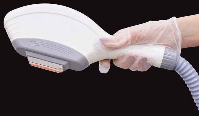 Gloved hand holding an IPL handpiece